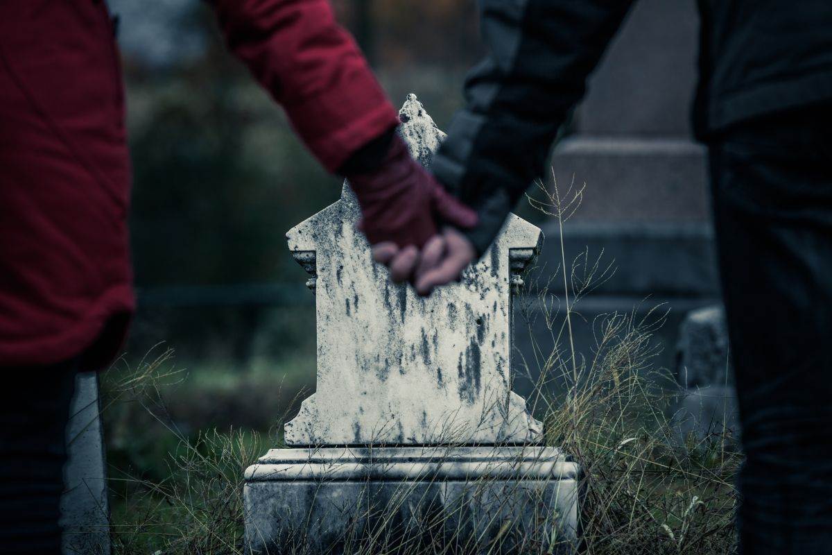 Par se drži za ruke na groblju 