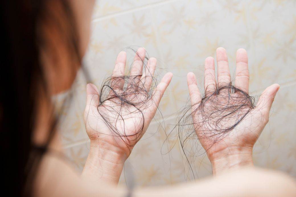  Žena drži kosu koja joj je opala 
